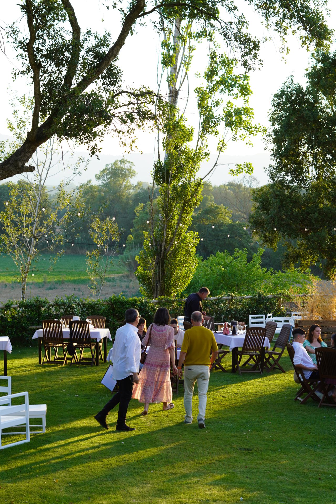 Atardecer sobre el jardín de Can Casellas con mesas preparadas